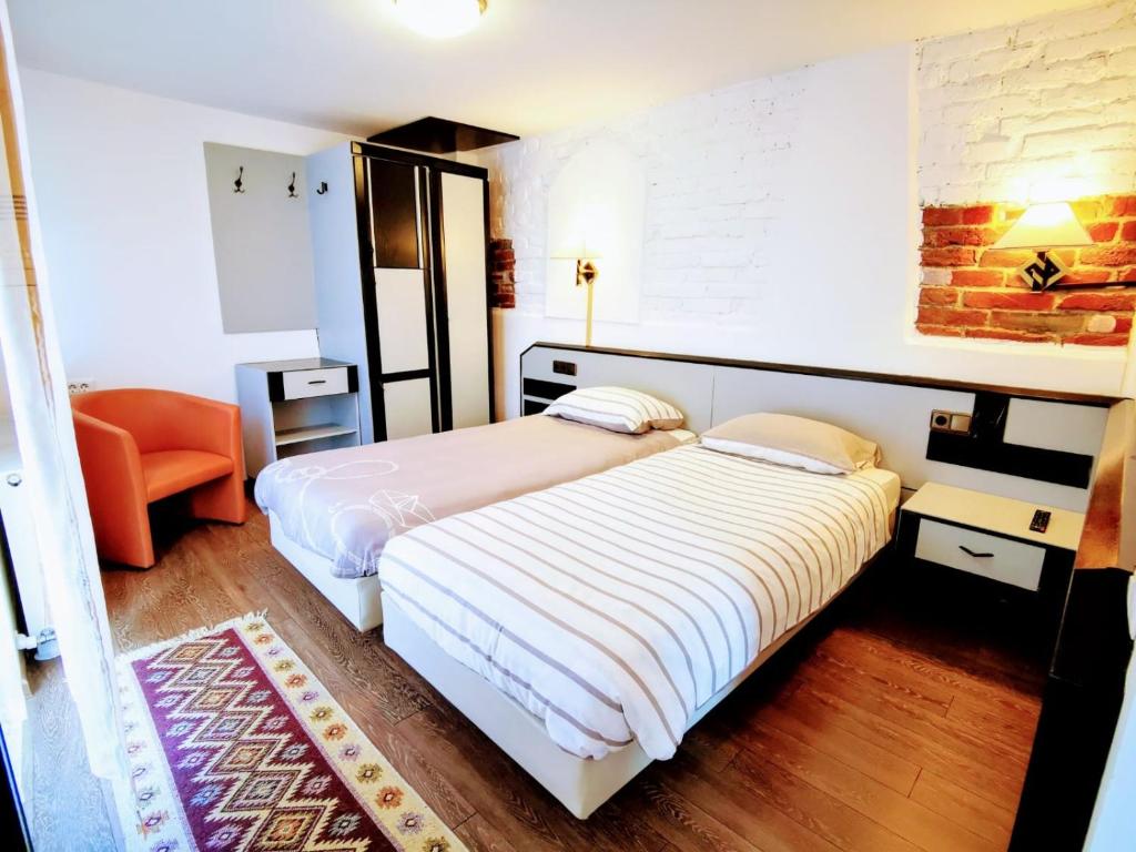 um quarto com 2 camas e uma cadeira laranja em studio em Sibiu