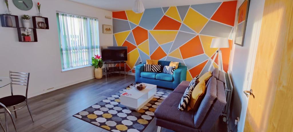 a living room with a blue couch and a geometric wall at The Pent House - Lushio Apartments in Northampton