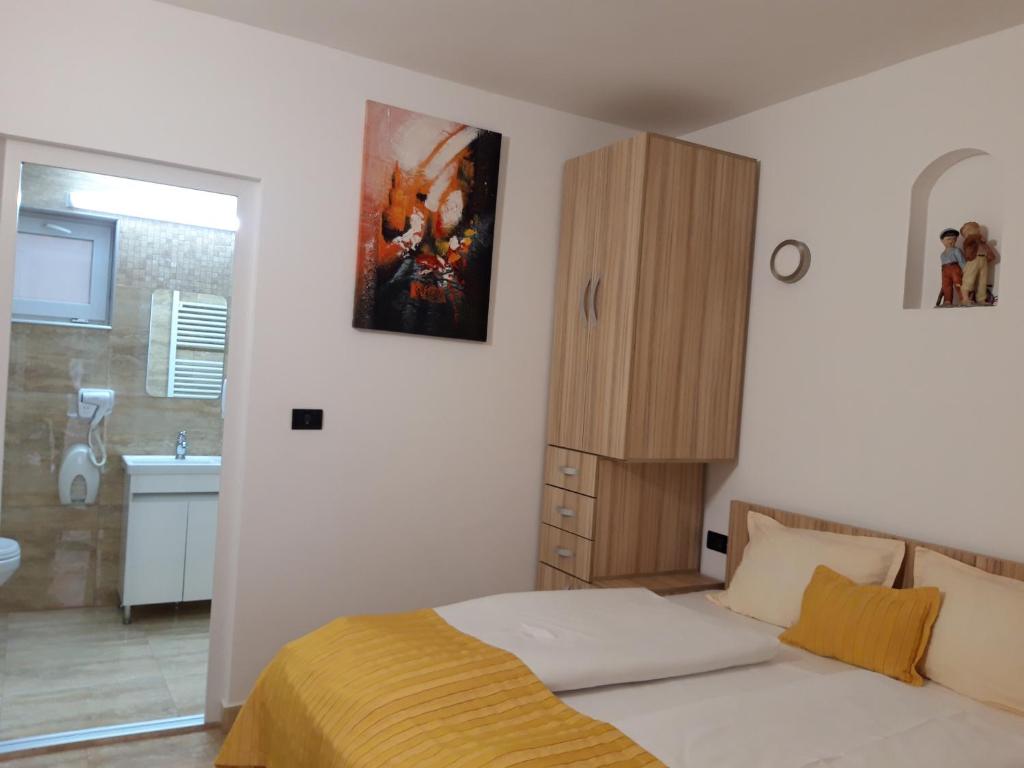 a bedroom with a bed and a cabinet and a bathroom at Apartament Sergiu Geanina in Micălaca