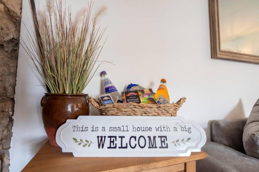 a small house with a big welcome basket on a table at Meadowhead Cottage, Traditional Scottish Cottage in Waterside