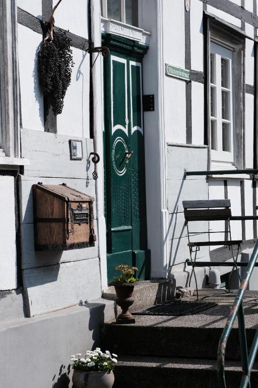 eine grüne Tür in einem weißen Gebäude mit einer Bank in der Unterkunft Ferienwohnung Am Schloßberg in Solingen