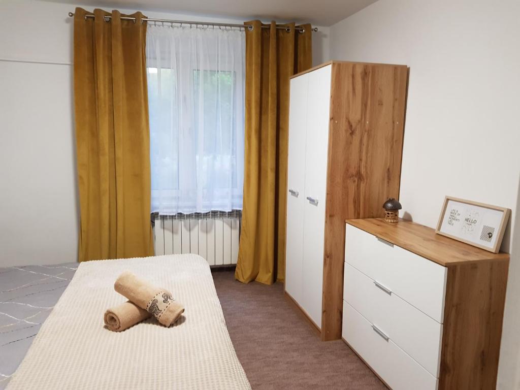 a bedroom with a bed and a dresser and a window at Apartament Wiejska Sielanka in Ryn