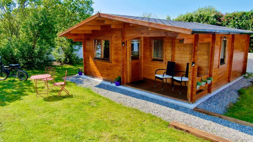 a wooden cabin with a table and chairs in a yard at Wild Atlantic Way Cabin in Ballyheigue