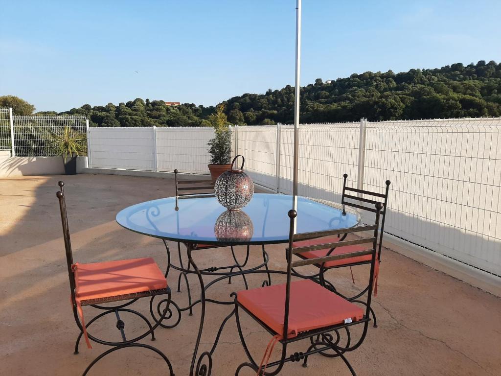 una mesa de cristal con 2 sillas y un jarrón en el patio en Villa_Culomba ALATA -T2 4 couchages en Alata