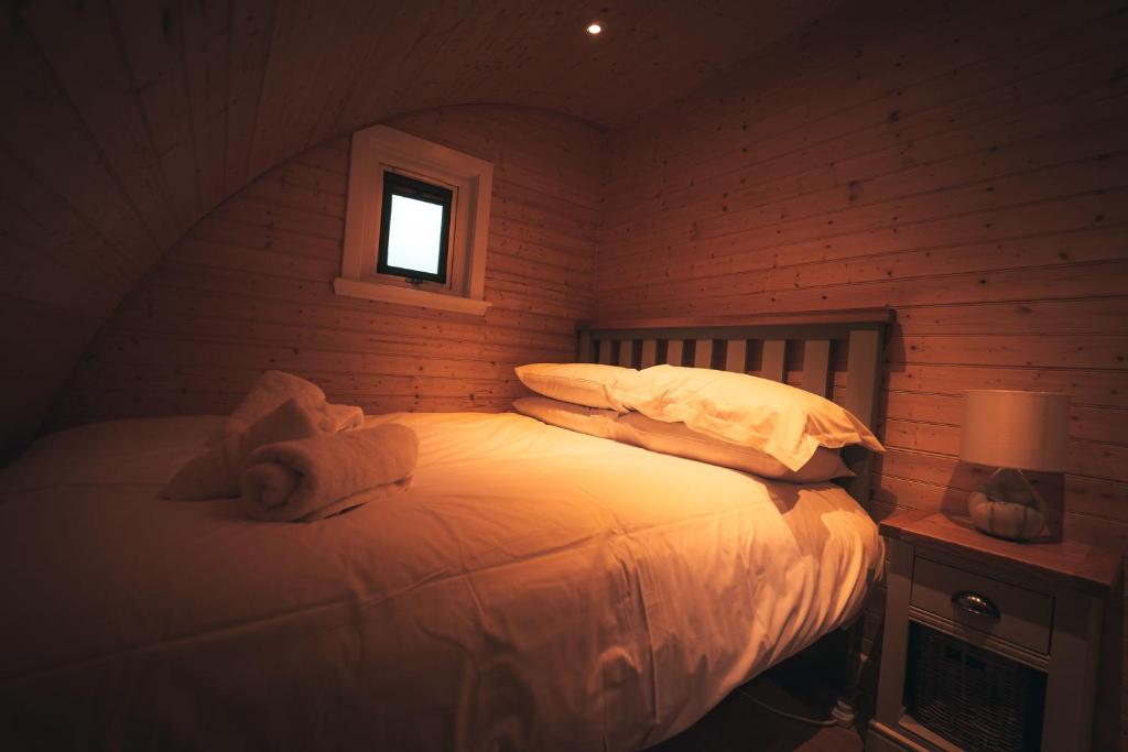 1 dormitorio con 1 cama con sábanas y almohadas blancas en Volcano Cabins, en Acharacle