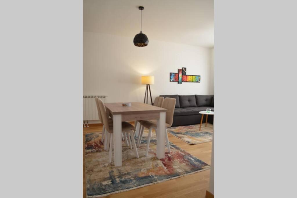 een woonkamer met een tafel en een bank bij Comfy New Apartment in Sarajevo