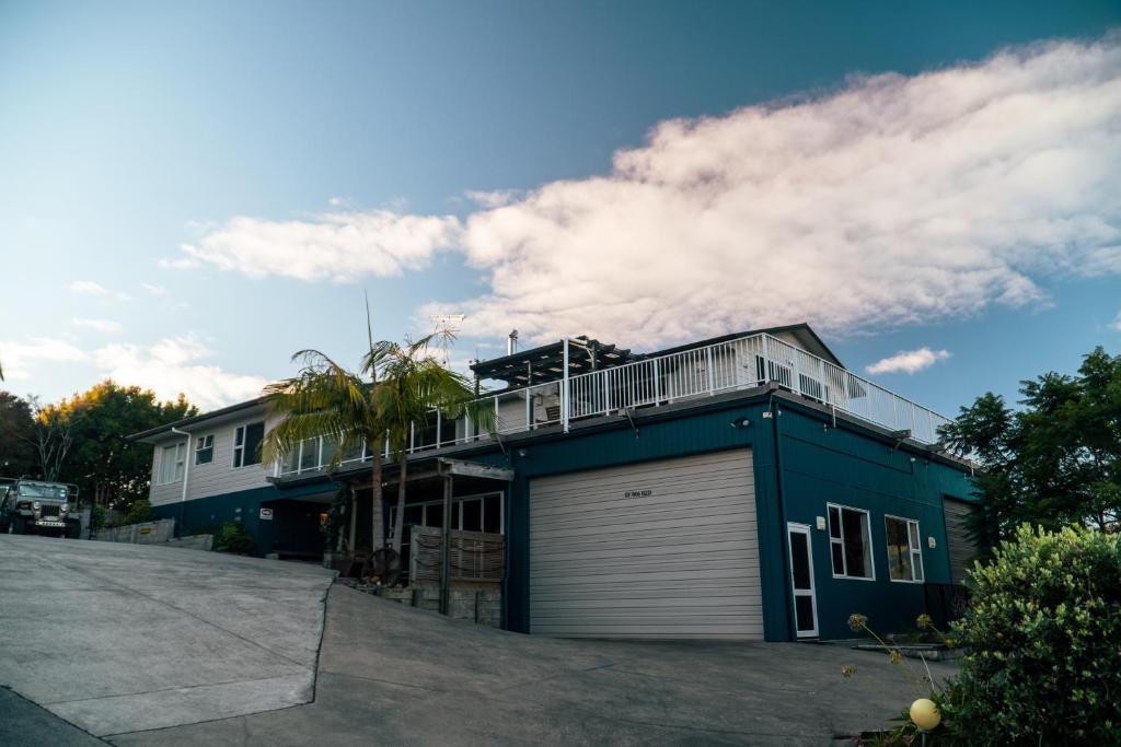 una casa azul con balcón en la parte superior en Coromandel Seaview Motel en Coromandel Town