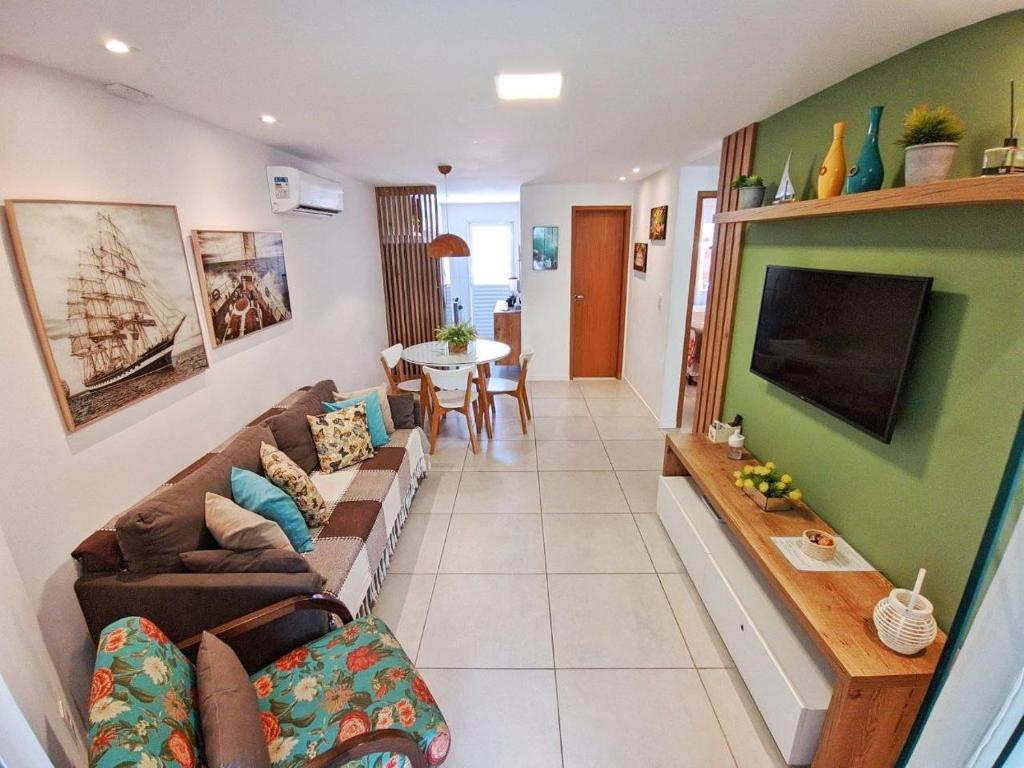 sala de estar con sofá y TV de pantalla plana en Guarajuba Porto Smeralda Village C02, térreo - GUARAJUBA TEMPORADA, viva mais de uma experiência de hospedagem conosco! 130m da praia, en Guarajuba