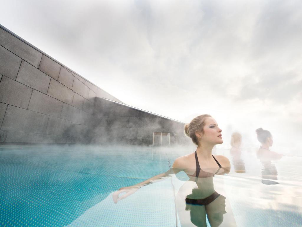 Eine Frau steht im Pool in der Unterkunft All In Resort Schwarzbrunn - 4 Sterne Superior in Stans