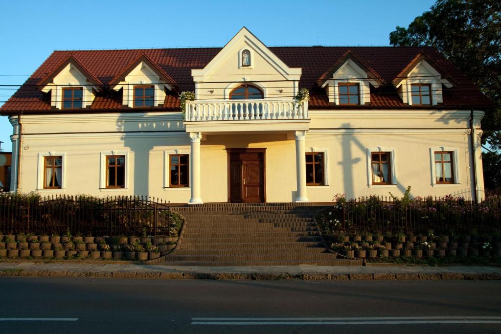 una gran casa blanca con una escalera delante de ella en Pokoje Gościnne w Ratuszu en Ogrodzieniec