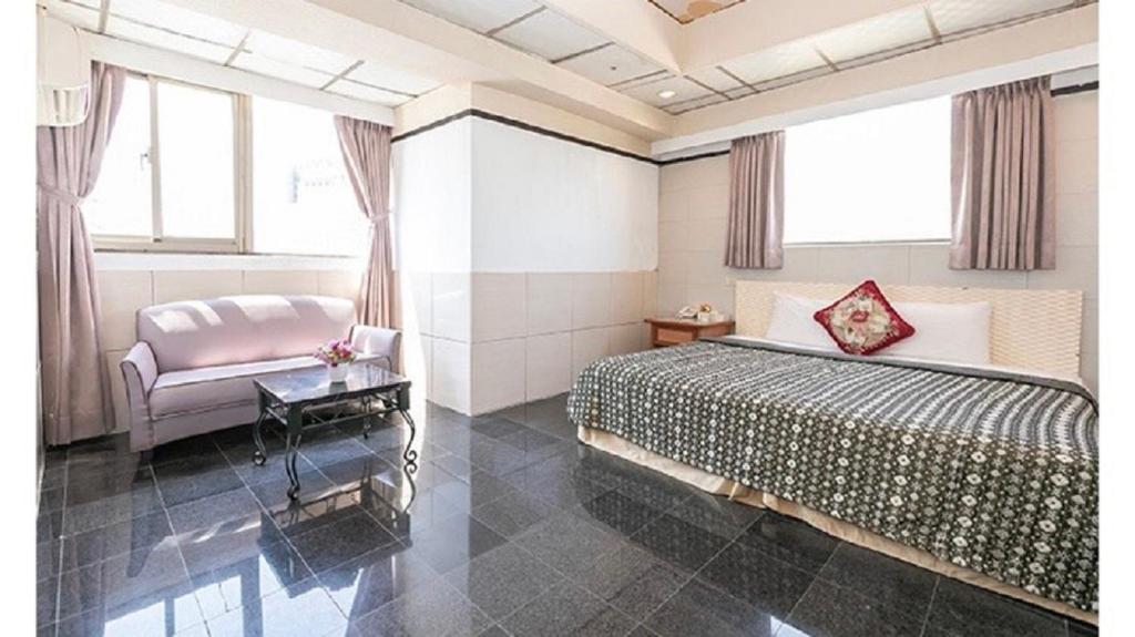 1 dormitorio con 1 cama y 1 silla en Yi Pin Business Hotel en Taoyuan