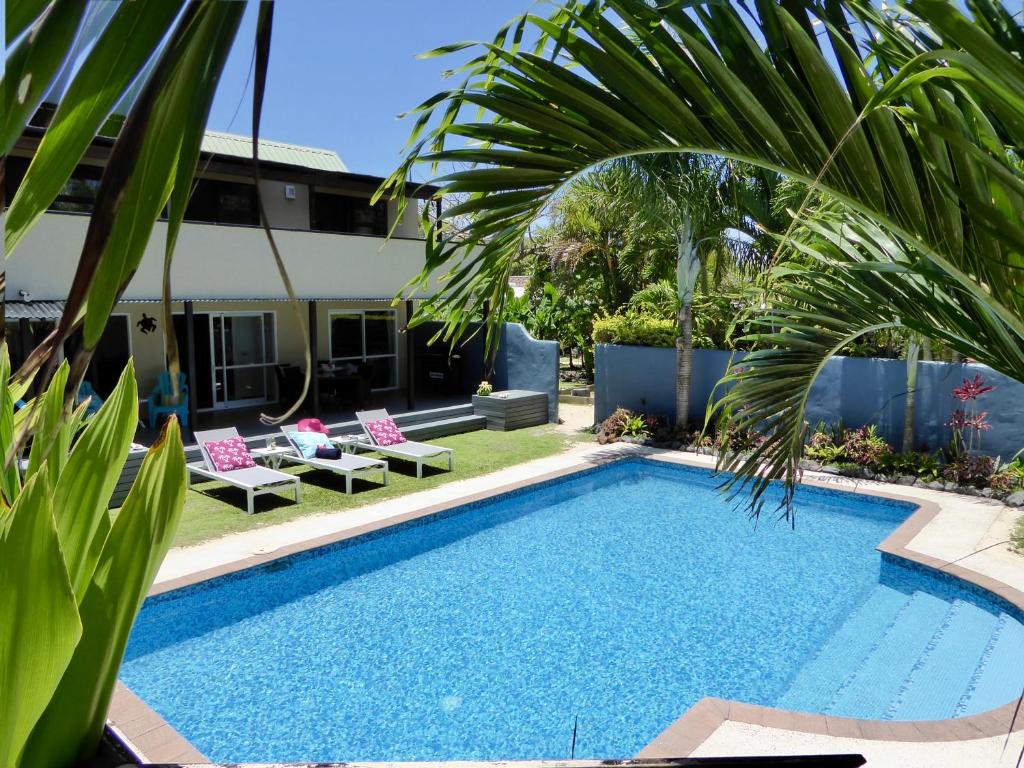 a swimming pool with chairs and a palm tree at Taakoka Muri Beach Villa in Rarotonga
