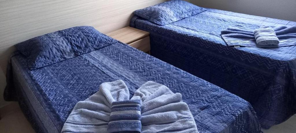 two twin beds in a room with blue comforter at Apartamento Diamante in Águas de Lindóia