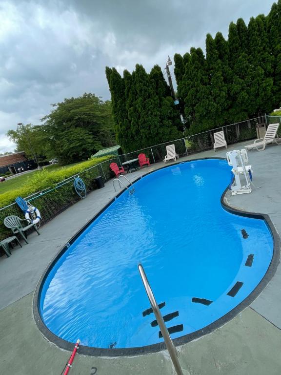a large blue swimming pool with chairs and trees at Scottish Inns Manchester in Manchester