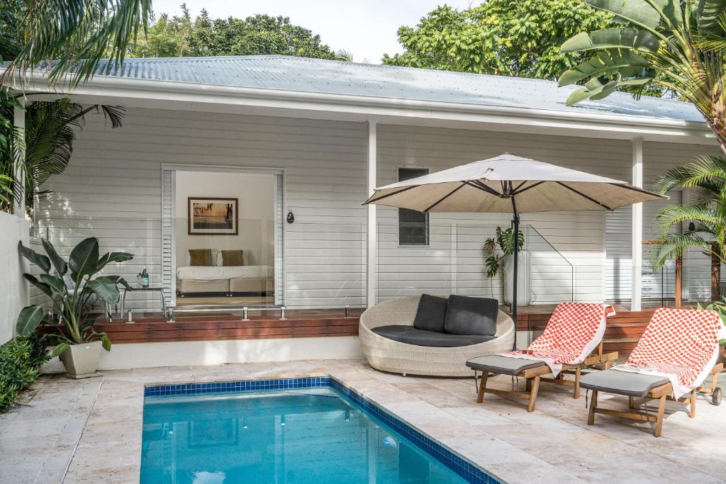 a swimming pool with two chairs and an umbrella at Cove Studios in Byron Bay