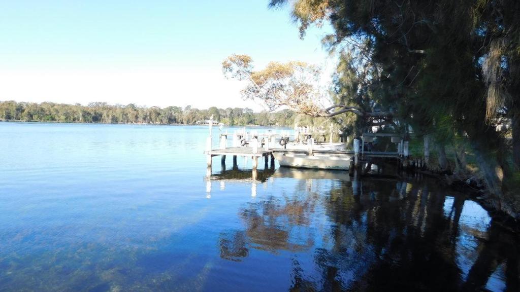 un muelle en un lago con un barco en el agua en Secret at Sussex Inlet Units, en Sussex Inlet