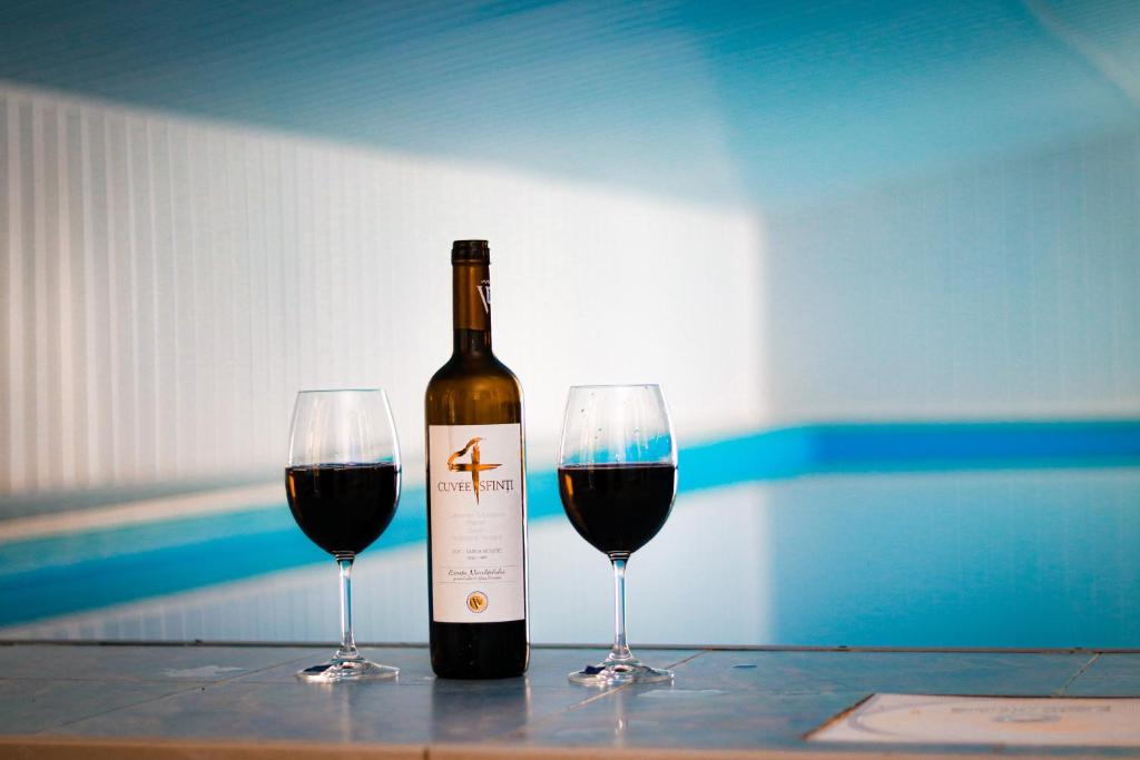 een fles wijn en twee glazen op een tafel bij Pensiunea Danieli in Eftimie Murgu