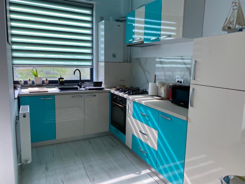 a kitchen with blue and white cabinets and a refrigerator at Ela's Apartment in Mamaia Sat/Năvodari