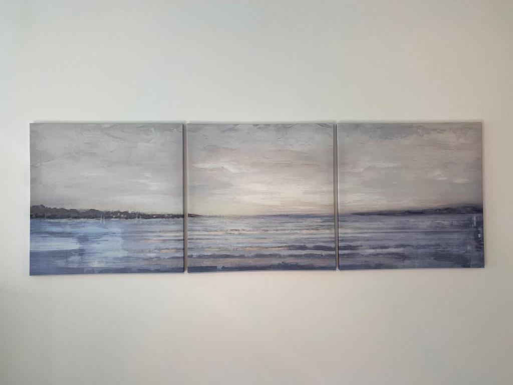 three paintings of the ocean on a wall at Ela's Apartment in Mamaia Sat/Năvodari