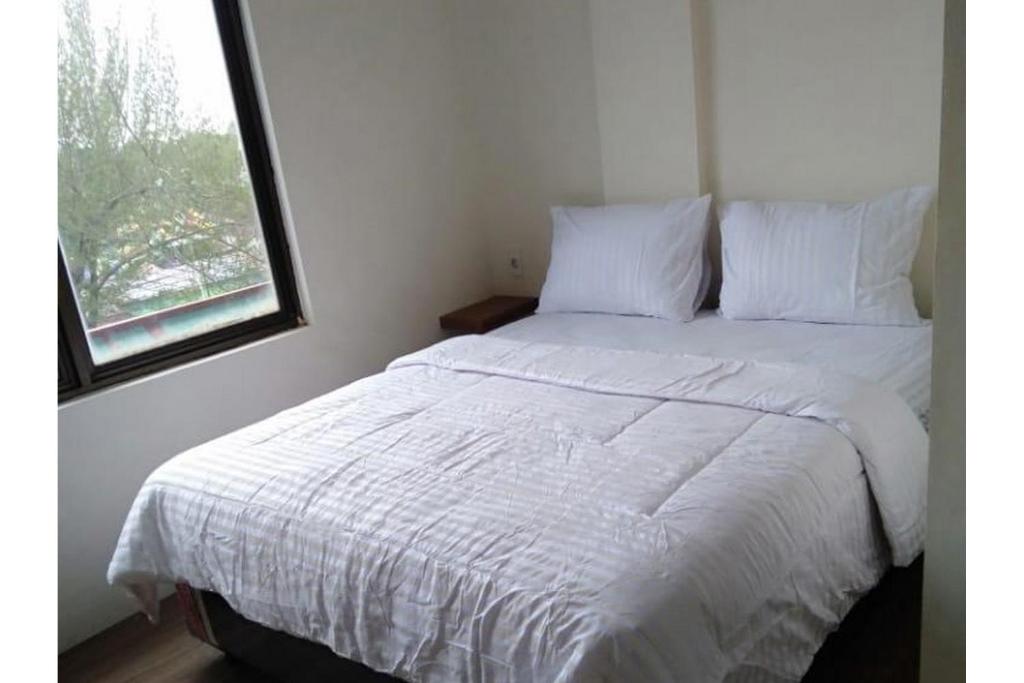 een wit bed in een kamer met een raam bij RedDoorz @ Komplek MMTC Deli Serdang in Pulauberayan Dadap