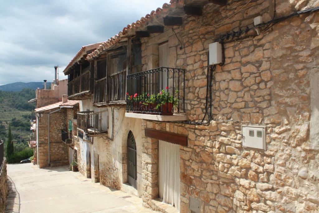 un edificio de piedra con un balcón con flores. en La casa de la flor. Un espai autèntic., en Ballestar