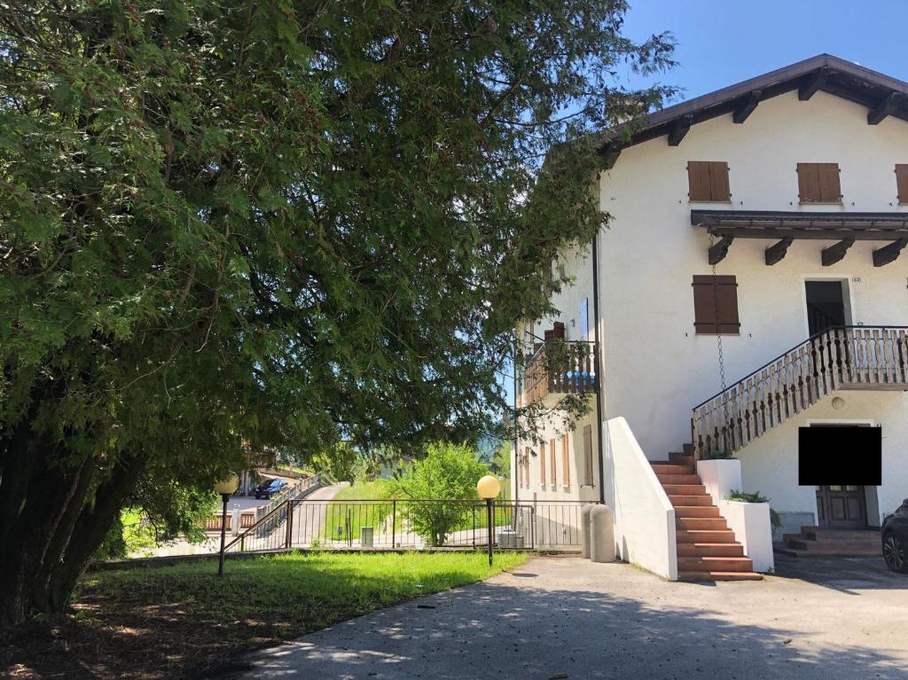 un gran edificio blanco con un árbol al lado en Alle Schiette, en Ponte nellʼAlpi