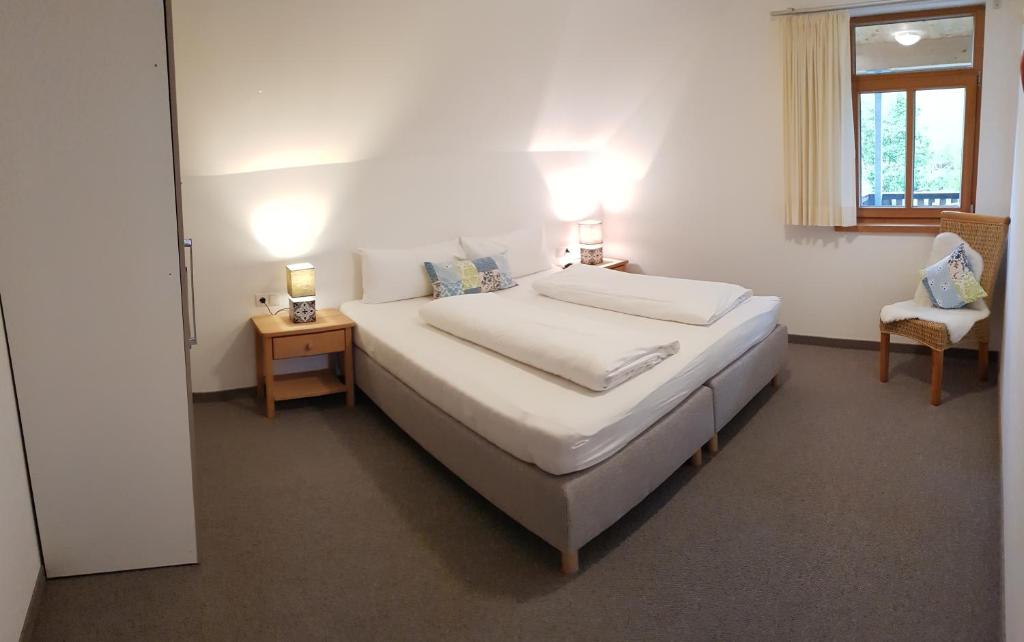 sypialnia z dużym białym łóżkiem i krzesłem w obiekcie Ferienwohnung Wüstner w mieście Schwarzenberg