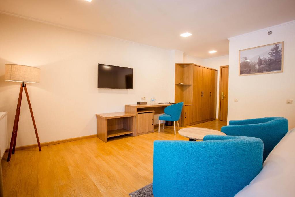 a living room with a desk and blue chairs at Gistola Hotel Mestia in Mestia