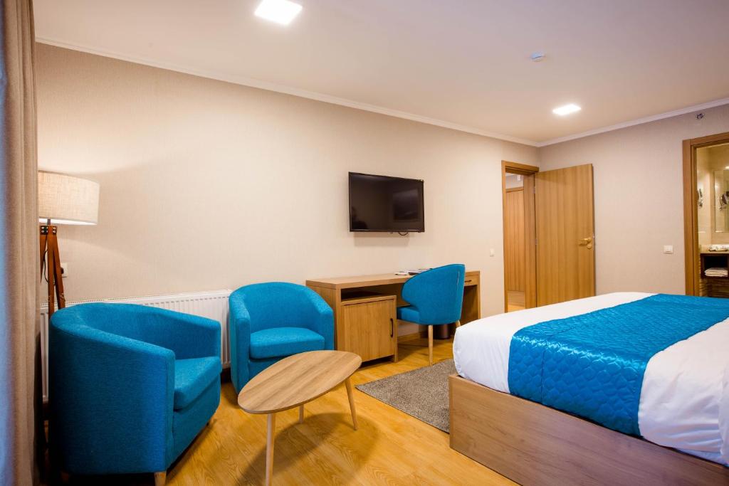 a hotel room with a bed and chairs and a desk at Gistola Hotel Mestia in Mestia
