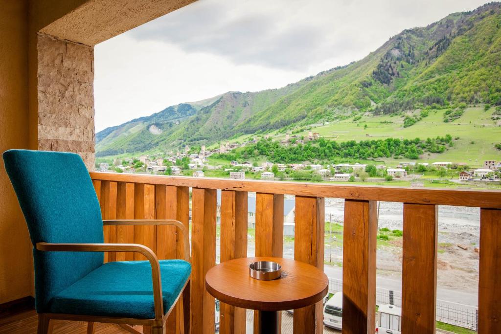 a balcony with a blue chair and a table and a view at Gistola Hotel Mestia in Mestia
