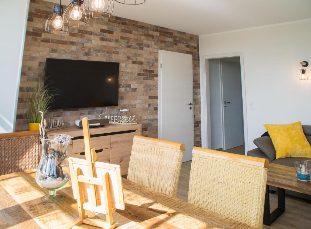 een woonkamer met een tafel en stoelen en een televisie bij Ferienappartement mit Seeblick in der Villa Columba in Ostseebad Sellin