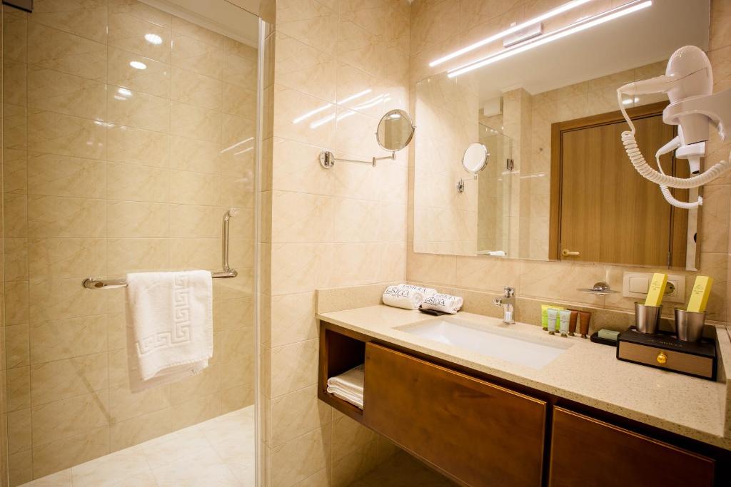 a bathroom with a sink and a shower with a mirror at Gistola Hotel Mestia in Mestia