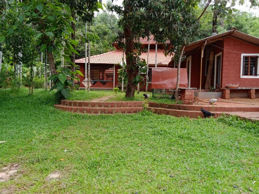 een klein rood huis met een boom in de tuin bij NIDHIVANA FARMS & RESORT, bakrebail-salethoor rd, Mangalore in Mangalore