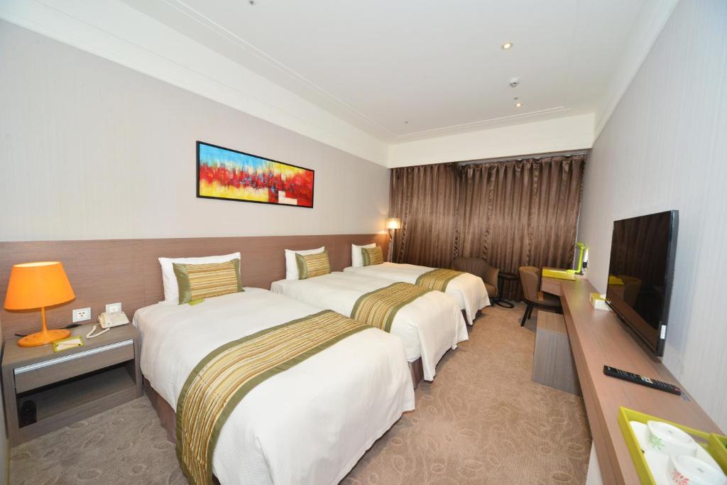 a hotel room with two beds and a flat screen tv at Grace Hotel in Zhonghe
