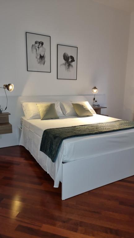 een wit bed in een witte slaapkamer met 2 lampen bij Villa Vittoria in Mesagne