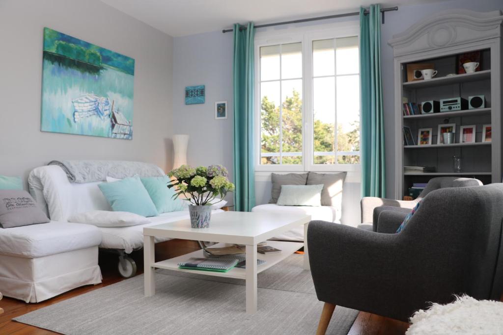 sala de estar con sofá blanco y mesa en La Source, en Hermanville-sur-Mer