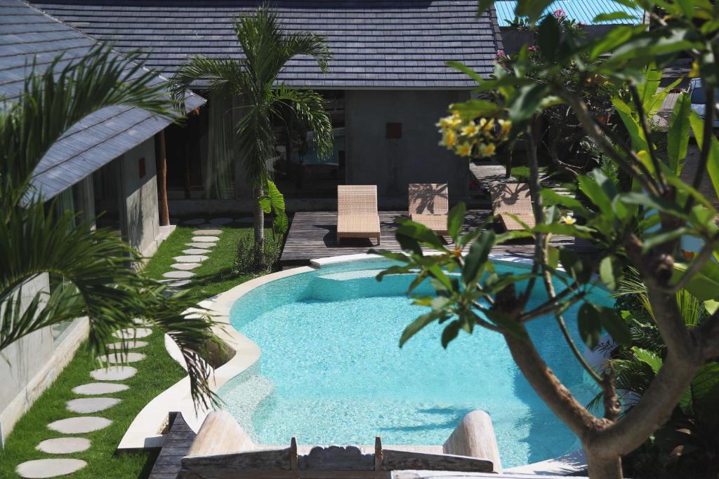 a swimming pool in a yard with palm trees at Kano Canggu Loft in Canggu