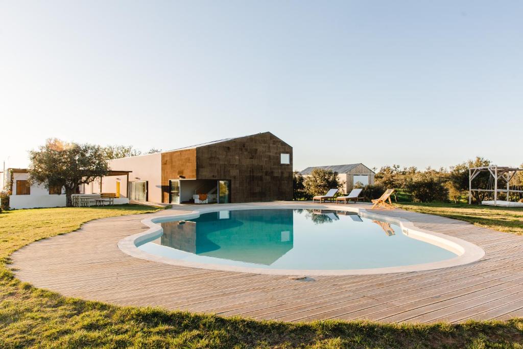 a swimming pool on a wooden deck in front of a house at Monte da Casa do João - Exclusive, private & fully serviced in Grândola