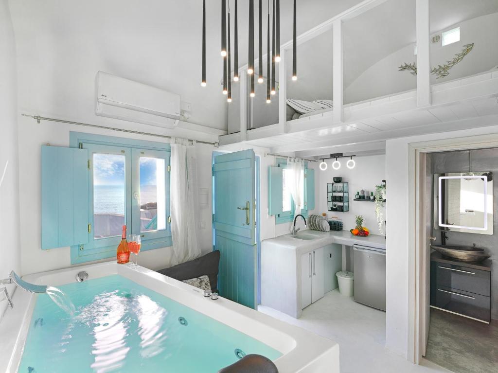 uma casa de banho com uma banheira azul e um lavatório. em Secret Gem Suites em Oia