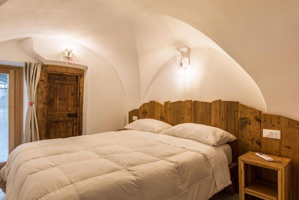 Schlafzimmer mit einem großen Bett mit einem Kopfteil aus Holz in der Unterkunft Logge dei Paroloti Paolo in San Lorenzo in Banale