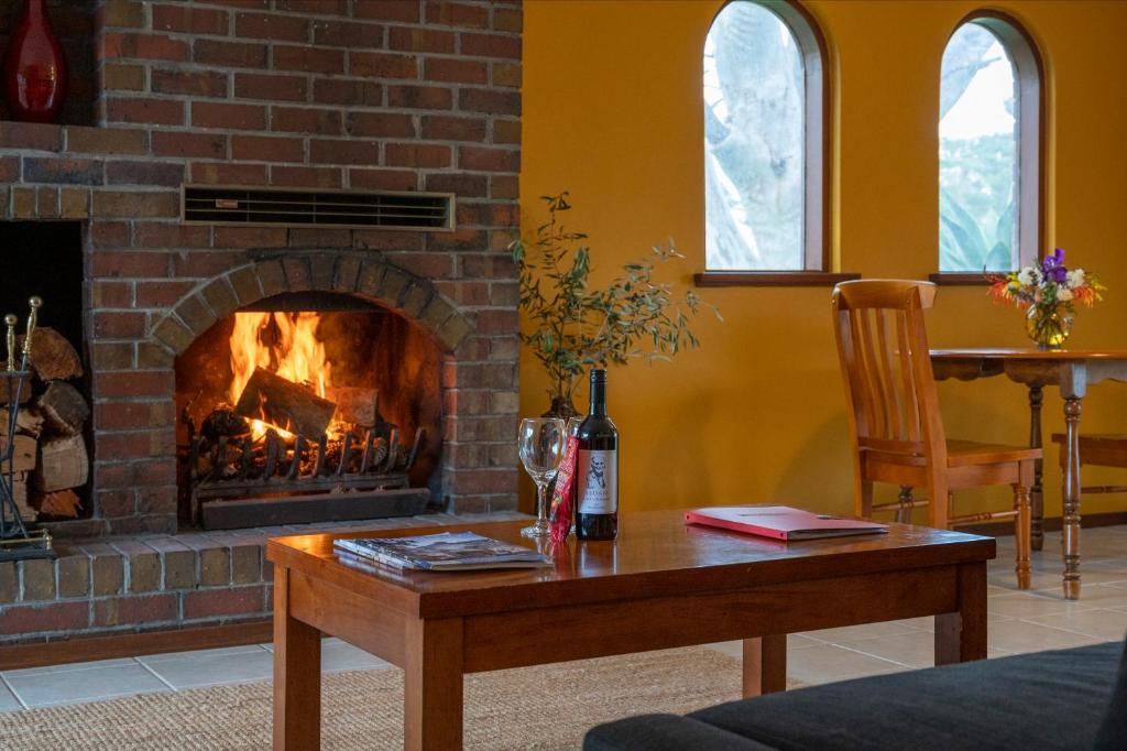a living room with a fireplace and a table with a bottle of wine at Linger Longer Vineyard in Willunga