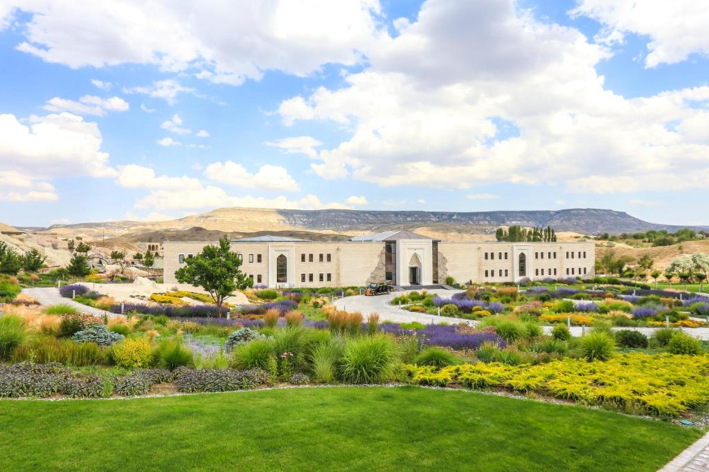 un jardín frente a un edificio con montañas en el fondo en AJWA Cappadocia, en Ürgüp