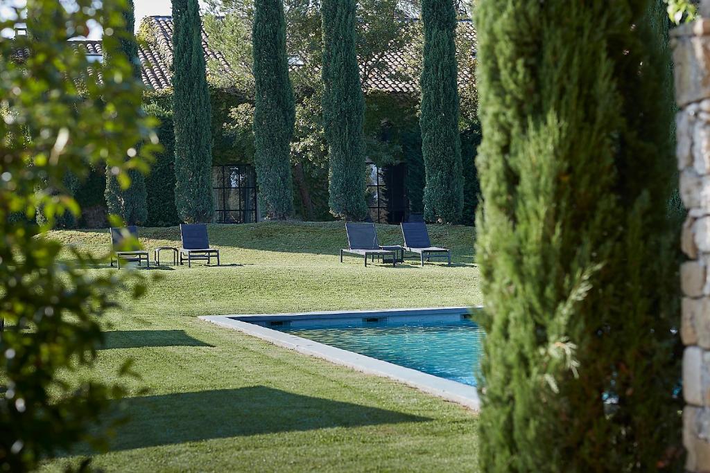 a swimming pool in a yard with chairs and trees at Mas des Songes in Monteux