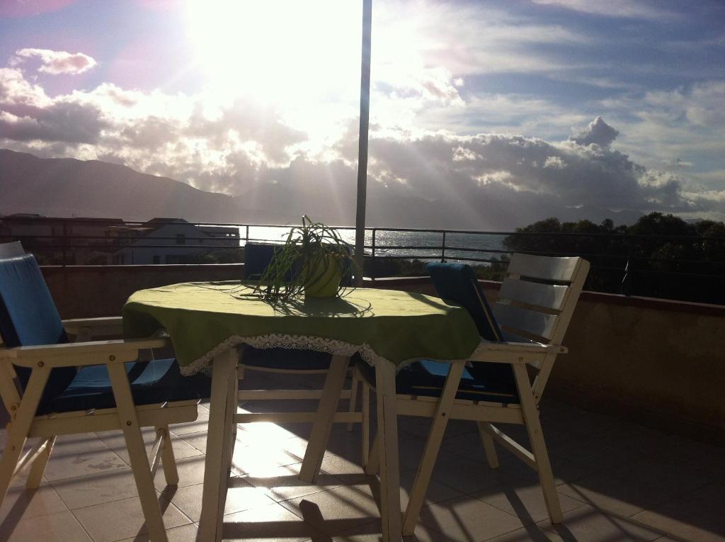 a table and chairs on a balcony with the sun shining at Casa Giulietta in Alcamo Marina