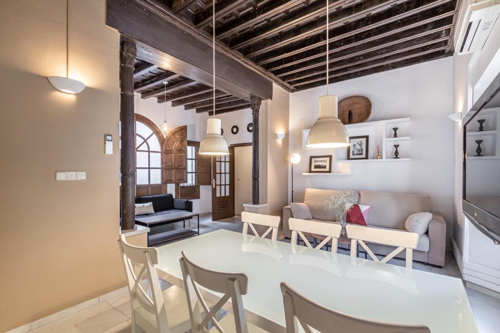 BnS Dauro Suites في غرناطة: غرفة طعام وغرفة معيشة مع طاولة وكراسي