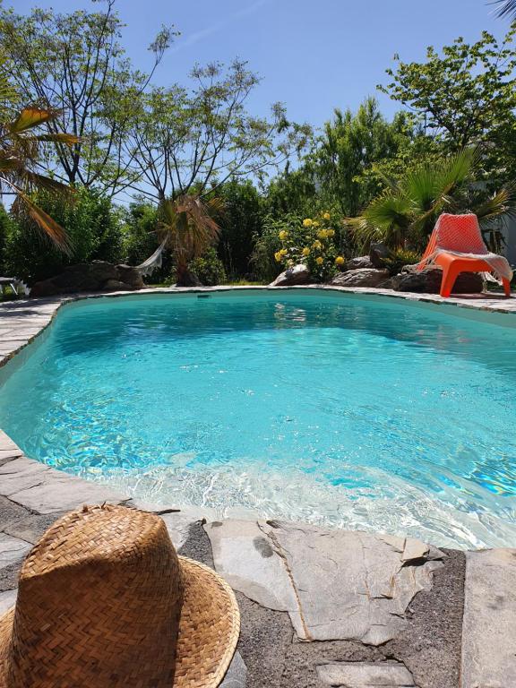 a swimming pool with a straw hat and a red chair at La Placeta Guesthouse in Pórtugos