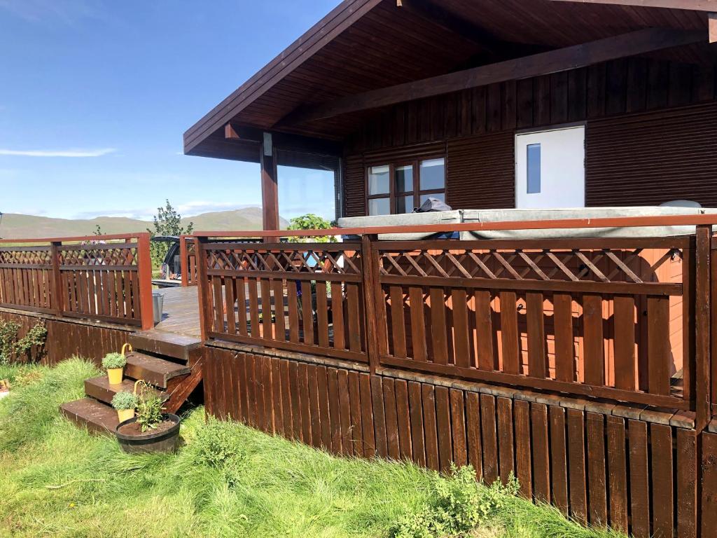une clôture en bois à côté d'une maison avec une terrasse couverte dans l'établissement Fögruvallakot Cabin, à Hella