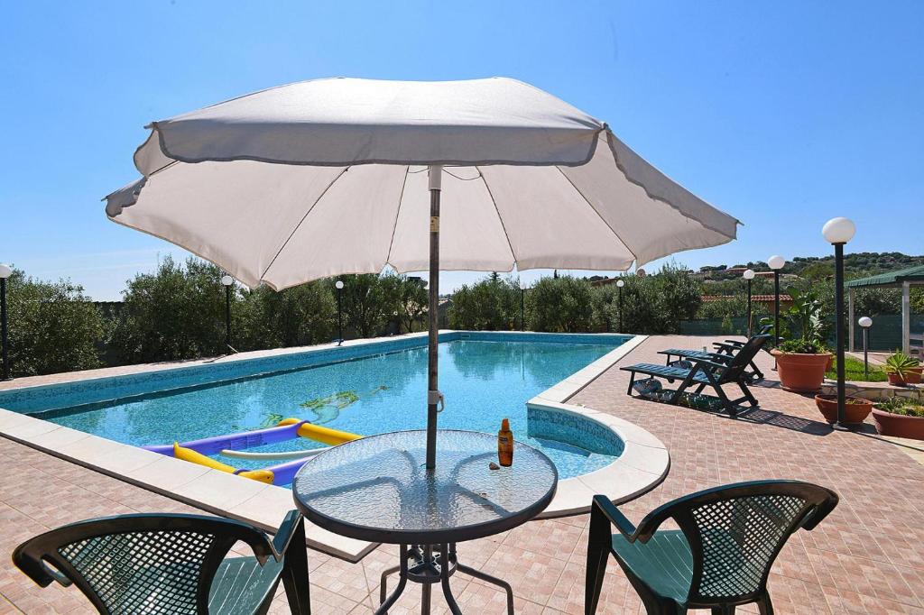 - une table avec un parasol à côté de la piscine dans l'établissement Holiday Home Floridia - ISI02266-F, à Floridia