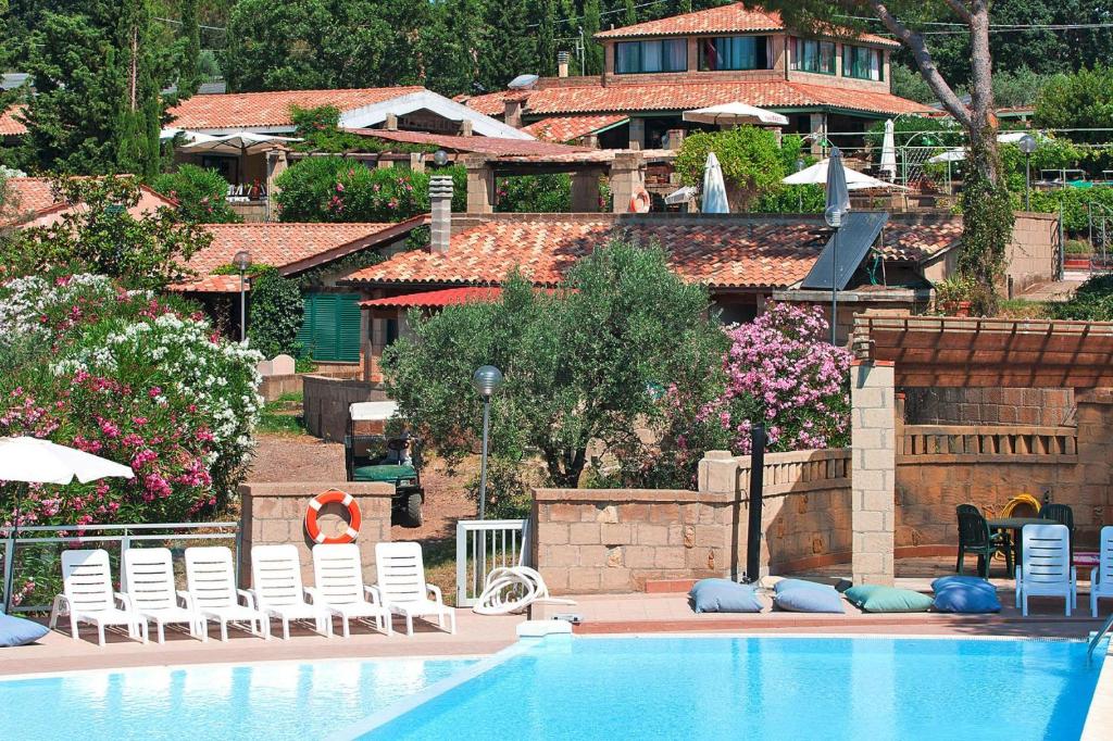 a swimming pool with white chairs and a house at Apartment in Guardistallo with heating in Guardistallo