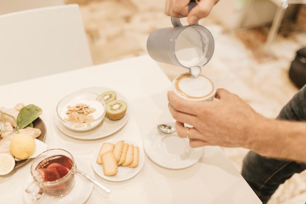una persona vertiendo café en una mesa con platos de comida en Giulietta nei Sassi, en Matera